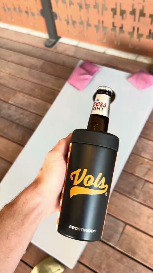 Lifestyle b-roll: a Vols Frost Buddy holding a Coors Light over a cornhole board