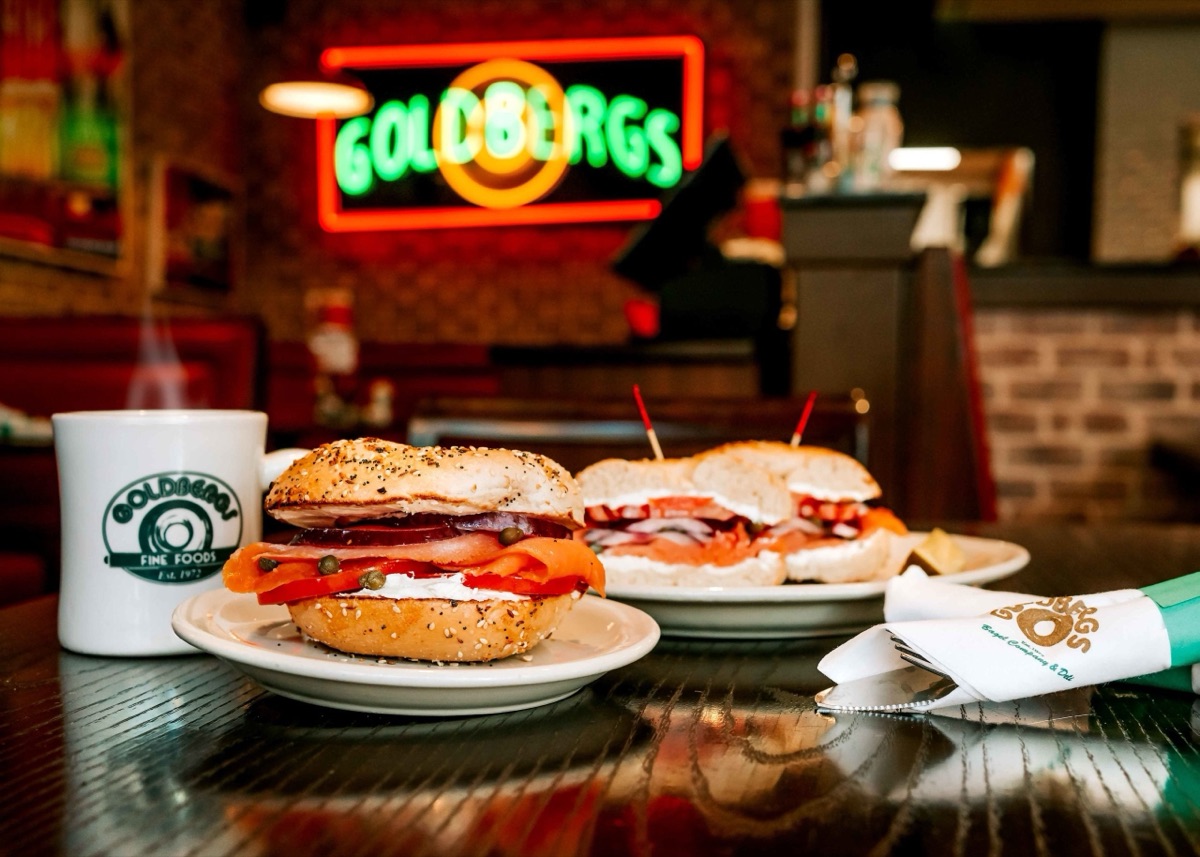 Bagel sandwiches under a neon sign, Goldbergs Fine Foods