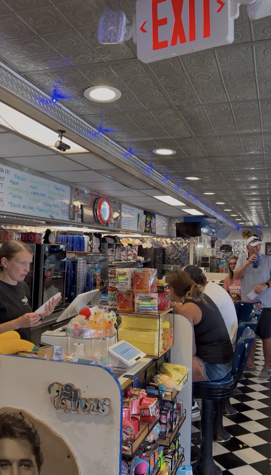Inside All American Diner, with counter stools, a checkerboard floor and the all-you-can-eat breakfast board on the wall