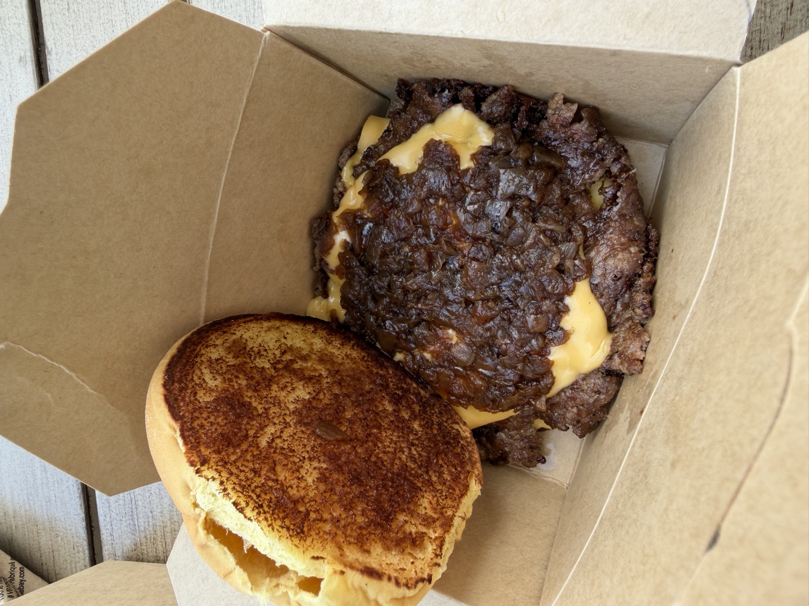 Sam's order: the Bad Luck Burger, a double smash patty with American cheese and caramelized onions in a paper box