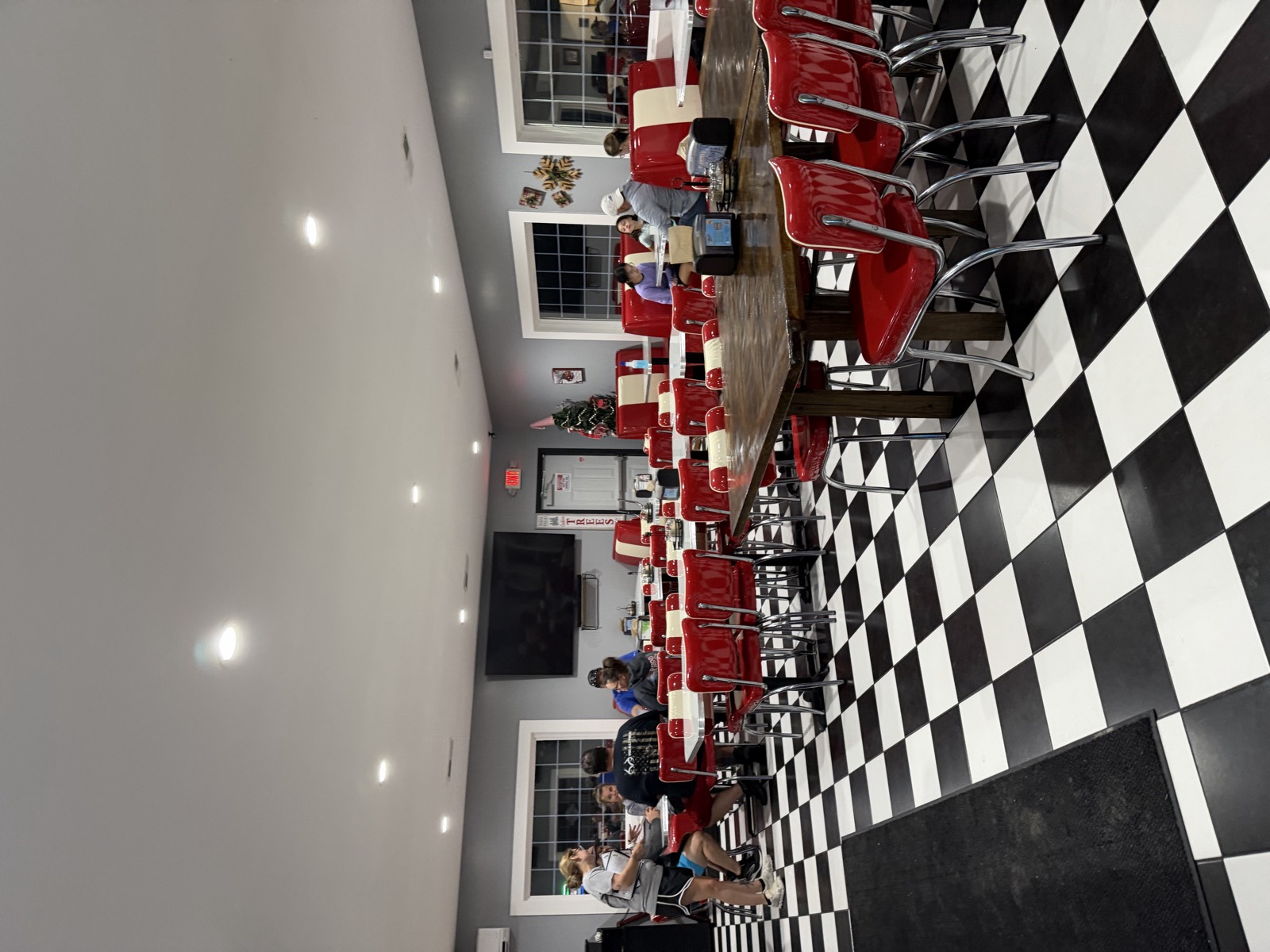 Inside Fat Santa's, with a black and white checkerboard floor, red diner chairs and a Christmas tree in the corner