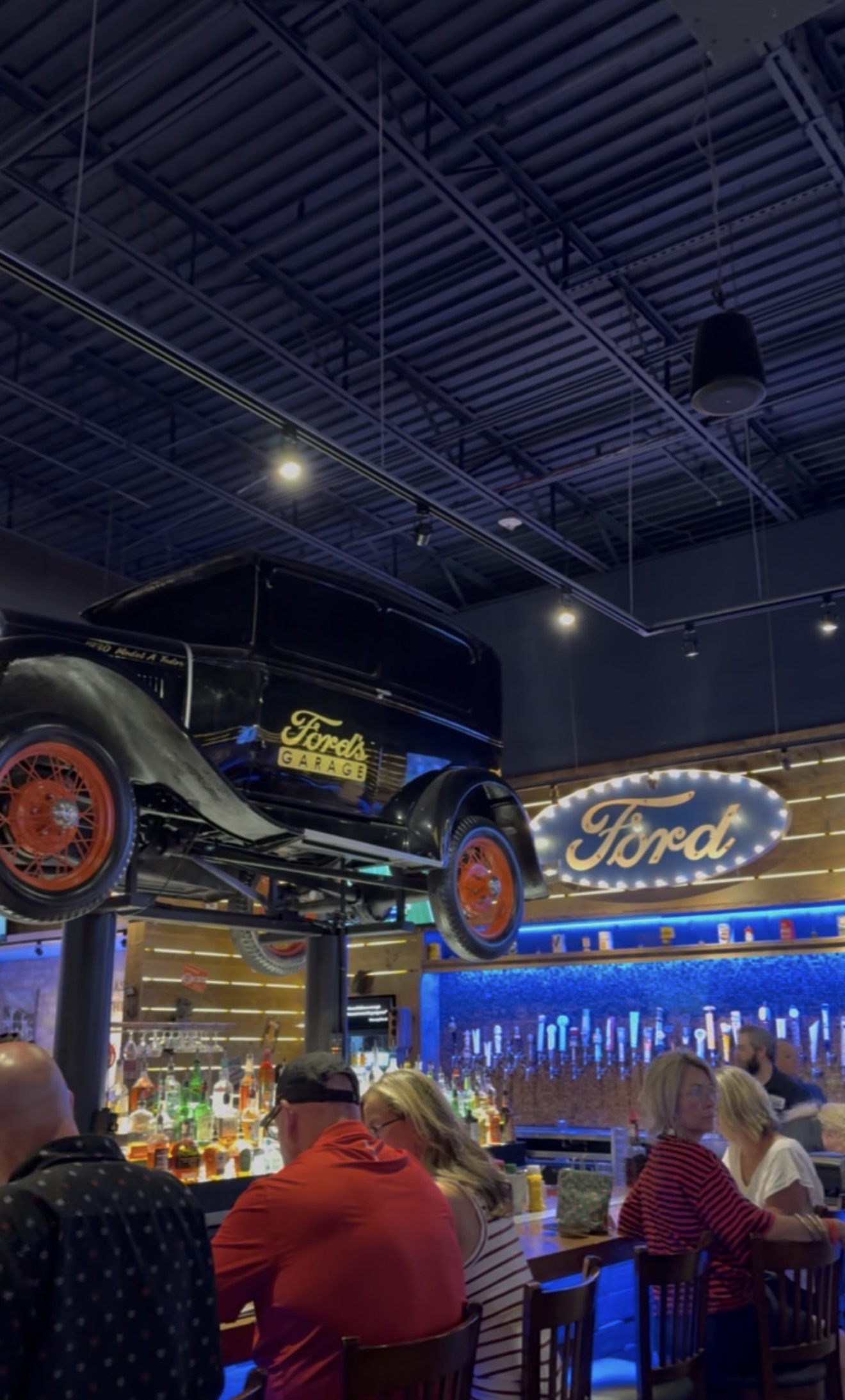 Vintage Ford Model A on a lift above the bar and beer taps at Ford's Garage
