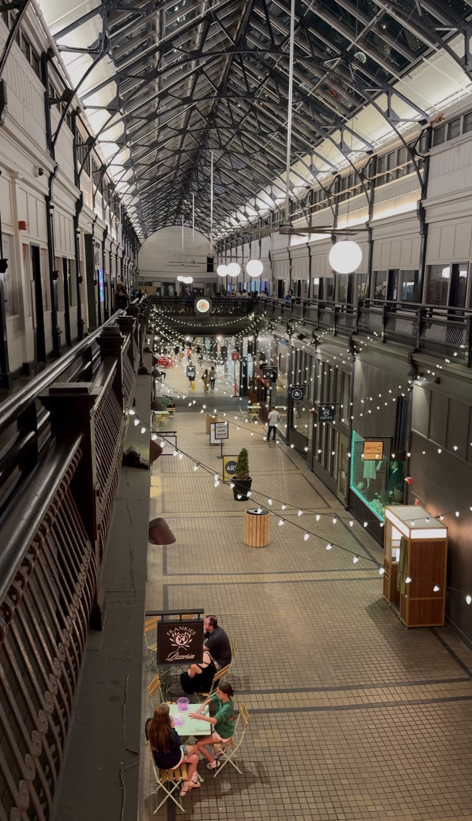 The Arcade in downtown Nashville from the upper level, with string lights under the glass roof and tables outside Frankies Pizzeria