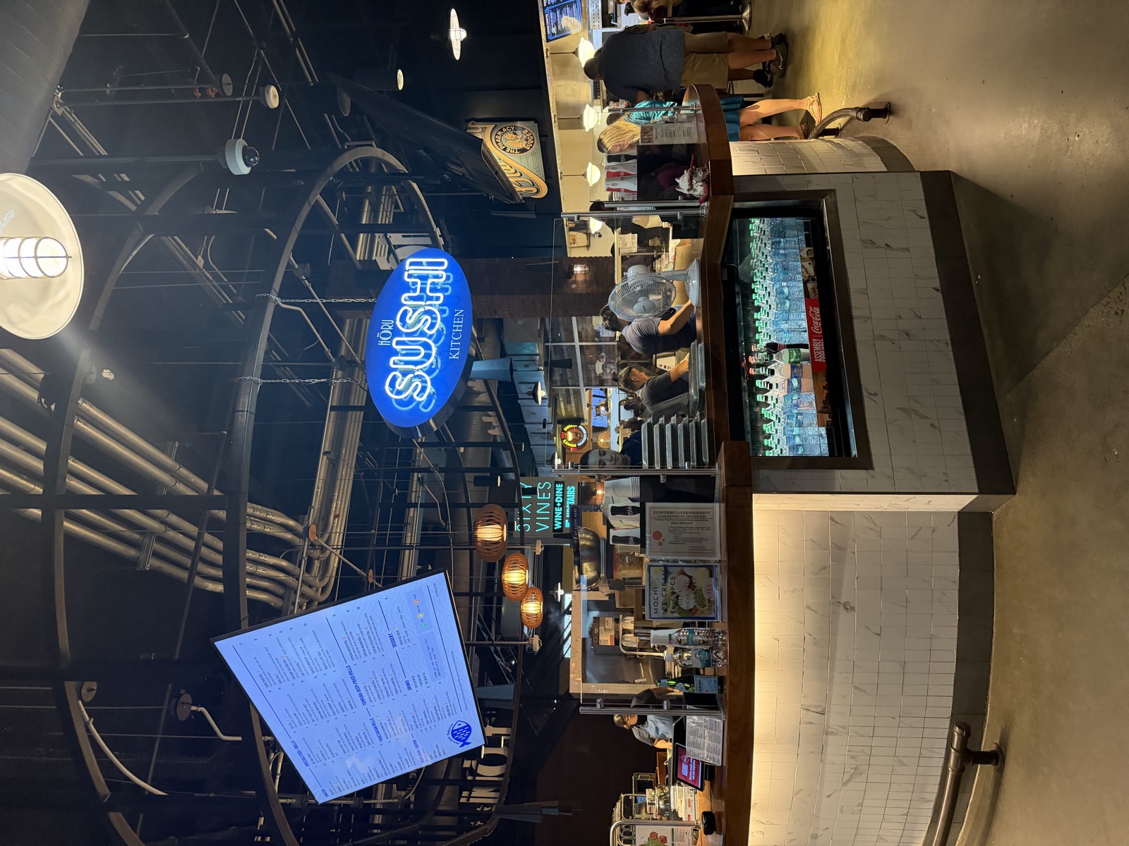 The Horu Sushi Kitchen counter inside Assembly Food Hall, under a blue neon sushi sign