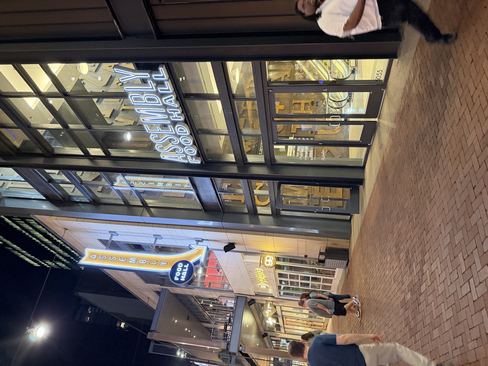 The Assembly Food Hall entrance at Fifth + Broadway at night, where Horu Sushi Kitchen is located