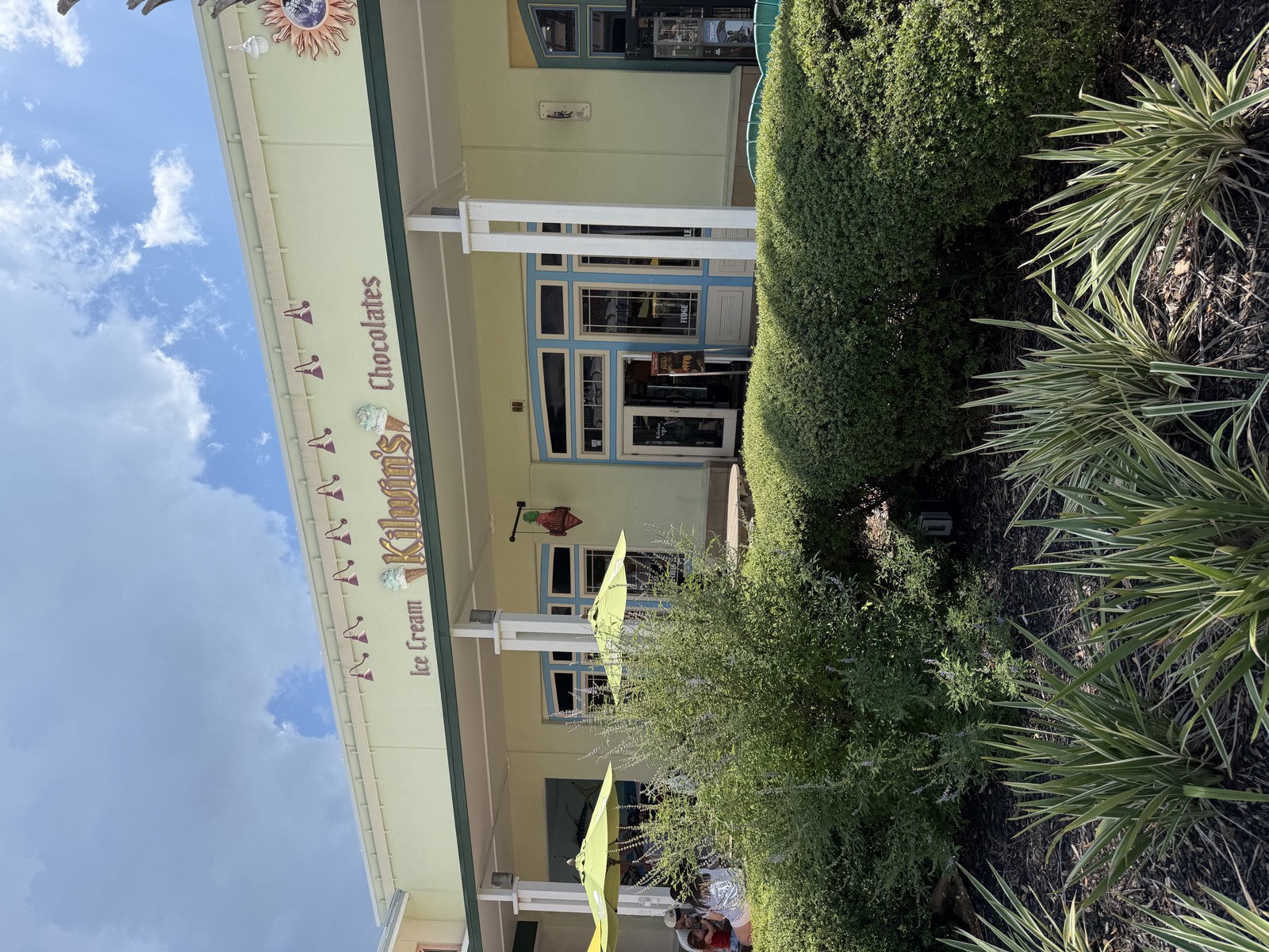Kilwin's storefront at Pier Park, with an Ice Cream and Chocolates sign and yellow patio umbrellas out front