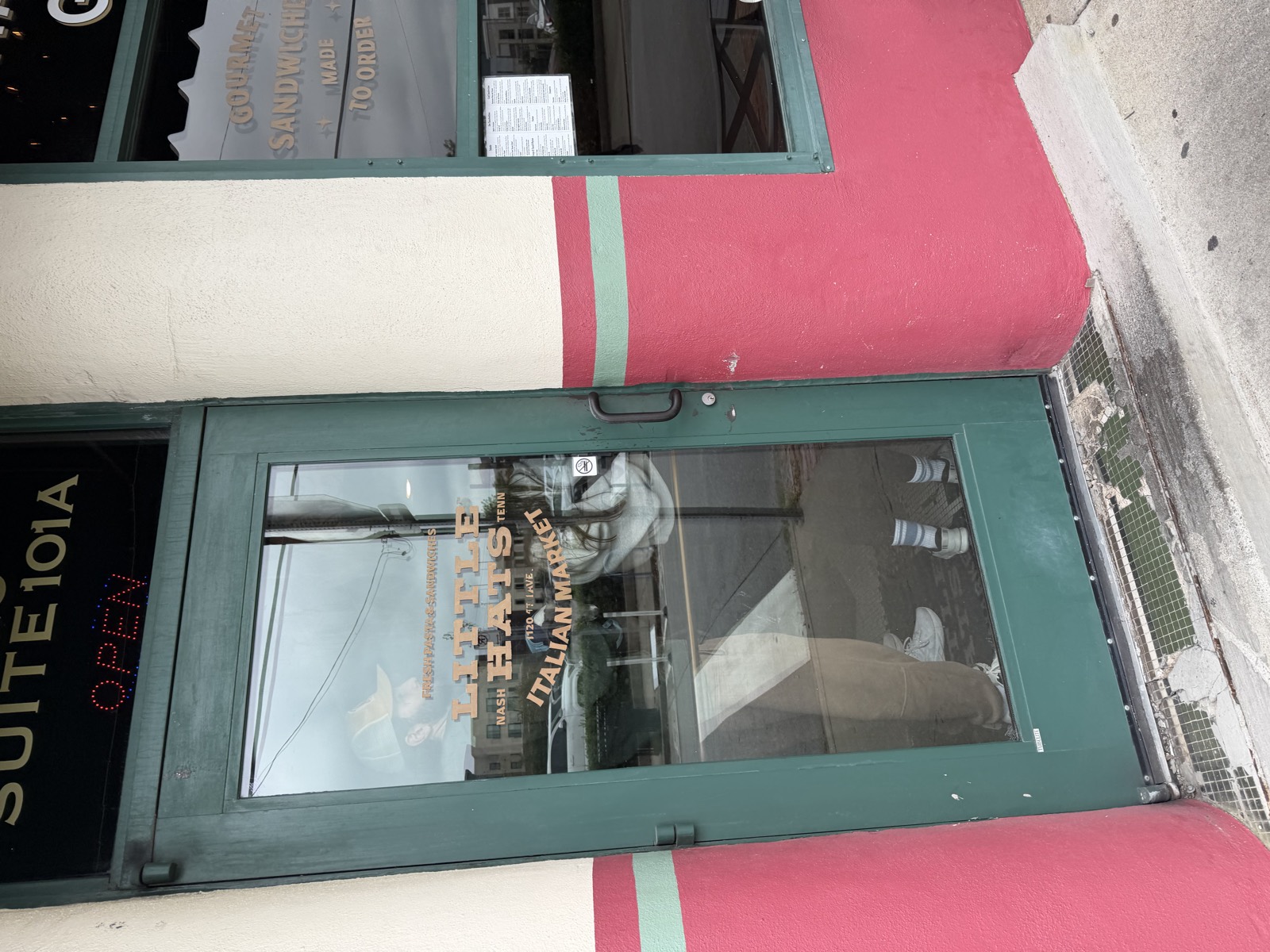The green door at Little Hats Italian Market in Germantown, with the logo on the glass and Suite 101A above it
