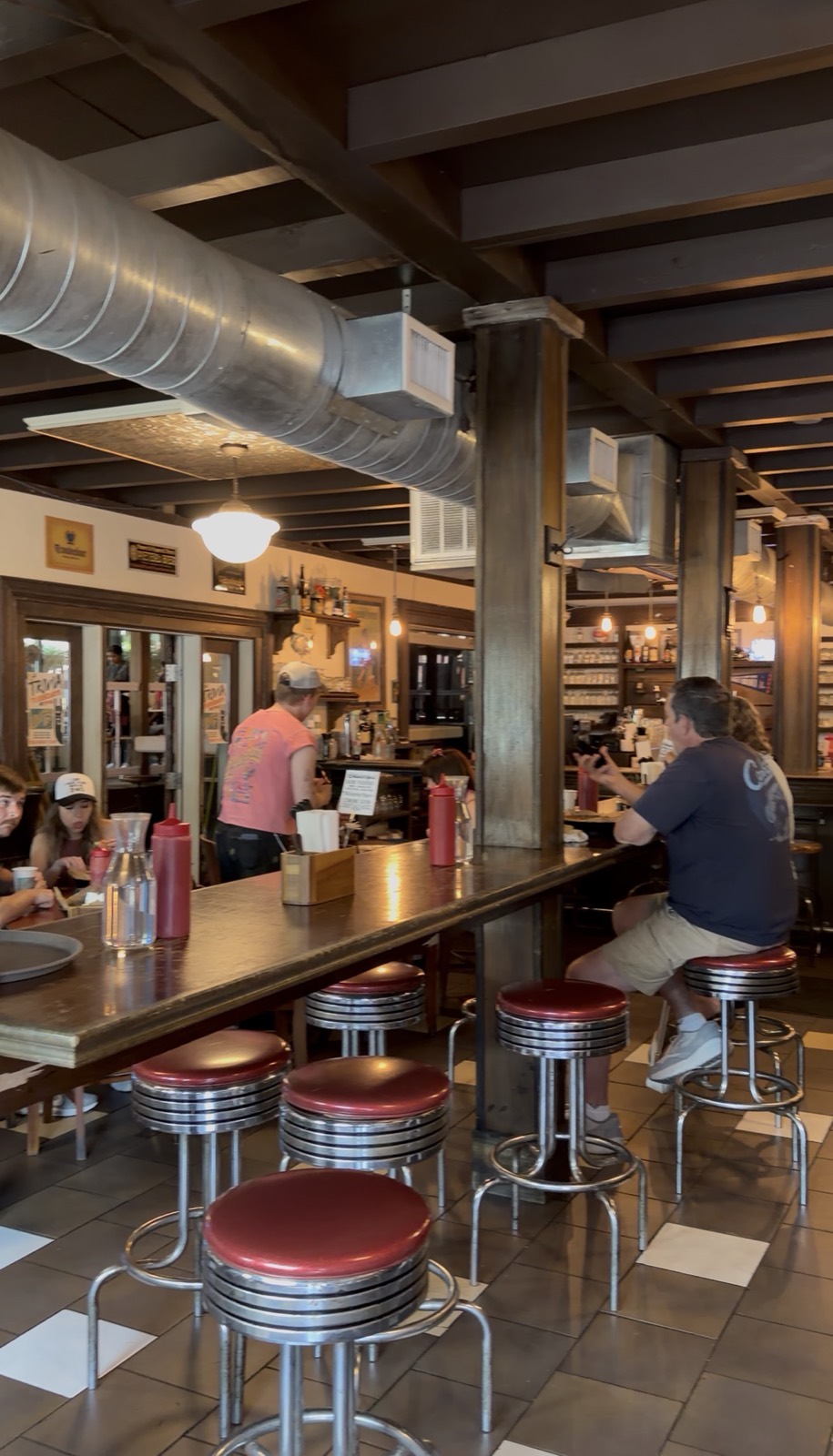 Inside The Pharmacy, with red soda fountain stools along a long wooden counter