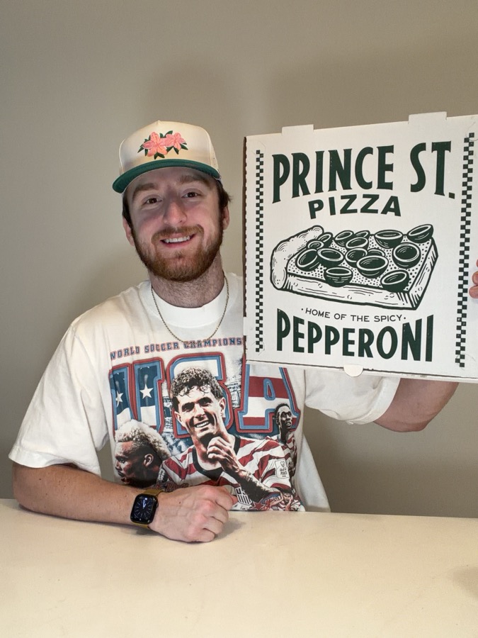 Sam holding a Prince St. Pizza box, home of the spicy pepperoni