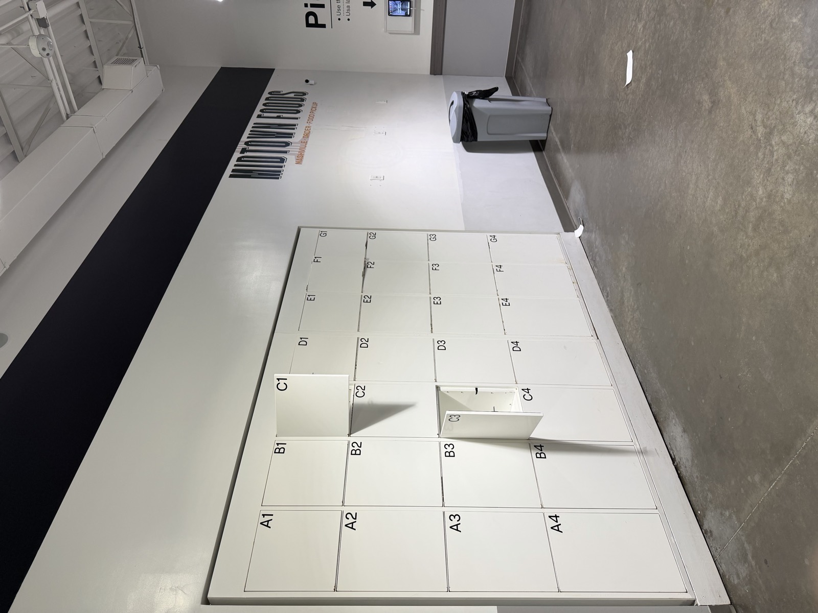 The wall of numbered pickup lockers inside Midtown Foods, with one hanging open