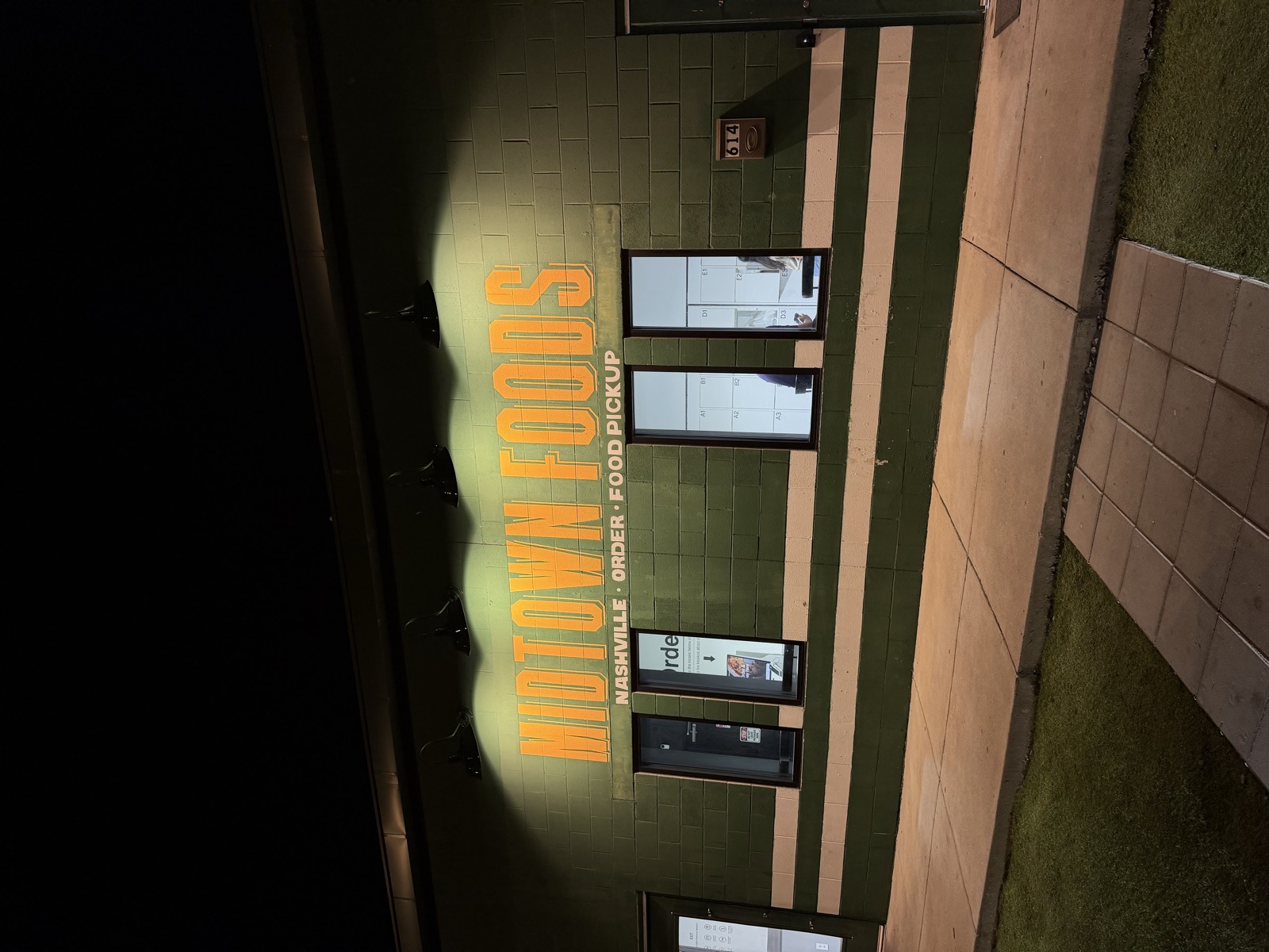 The Midtown Foods building at night, where Sabor Corazón cooks, with an orange Nashville Order Food Pickup sign