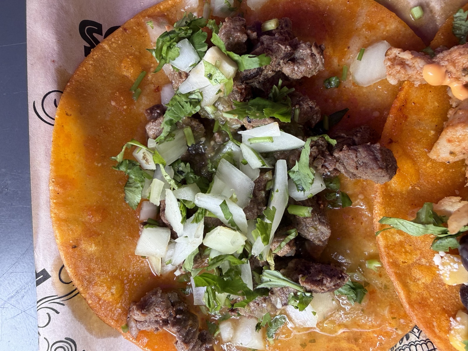 Sam's order: the Carne Asada taco topped with onion and cilantro on an orange tortilla