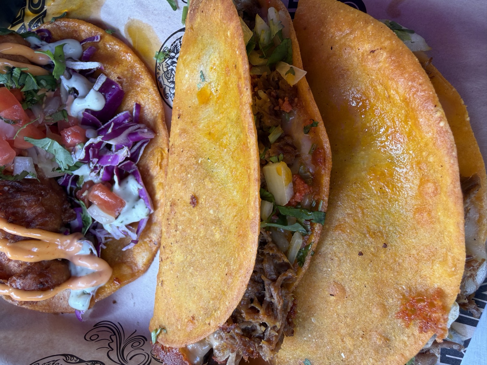Sam's order: a Taco Trio on the tray, with folded birria tacos in front of a shrimp taco