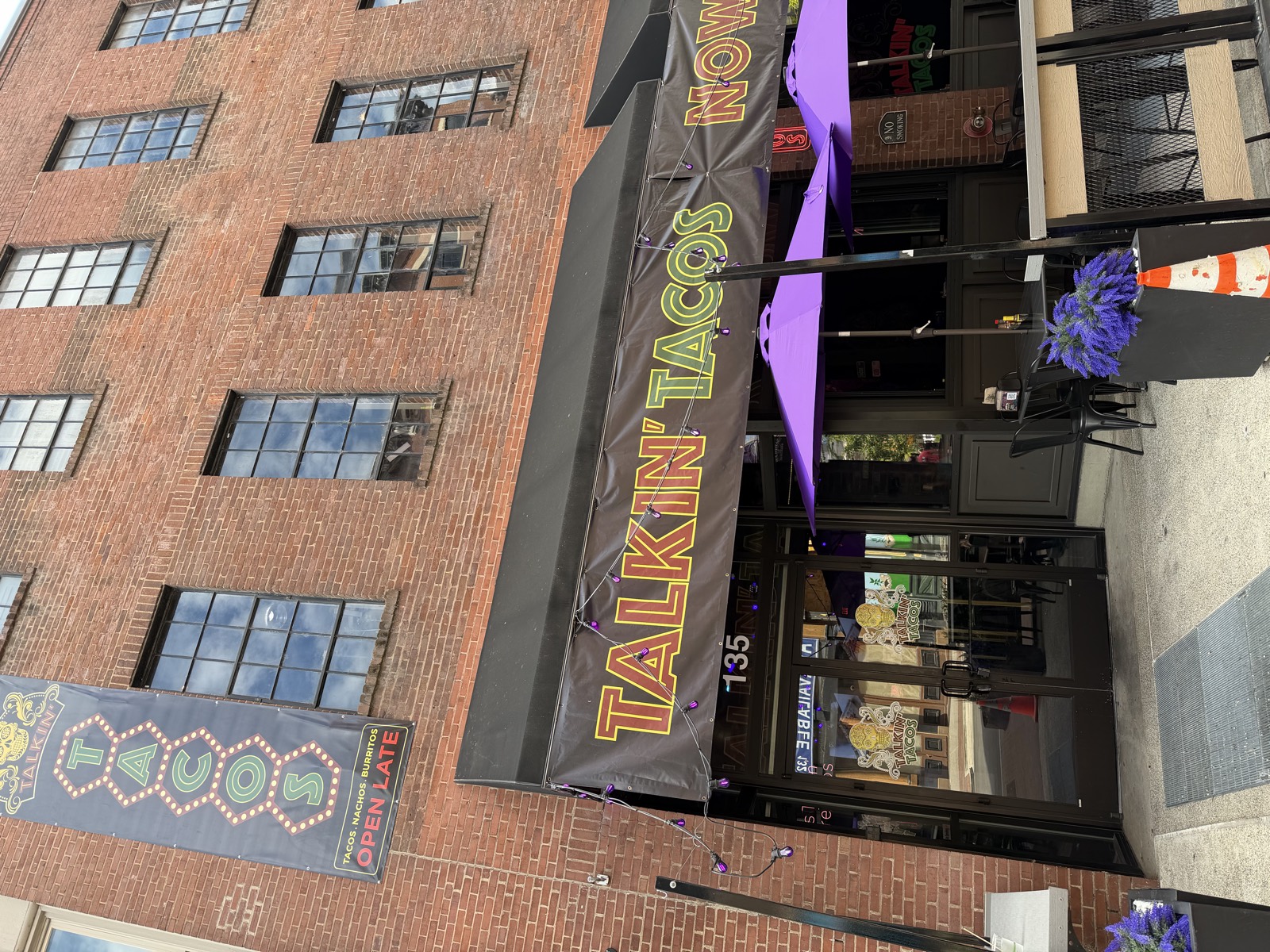 Talkin' Tacos on 2nd Avenue North, with a black awning, an Open Late sign and purple patio umbrellas out front