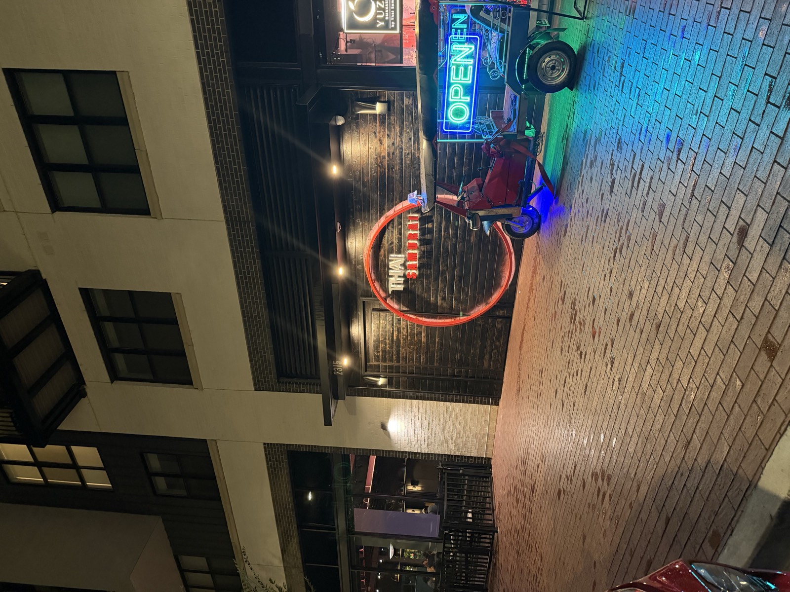 Thai Samurai River North entrance at night, with a neon sign and a tuk-tuk out front